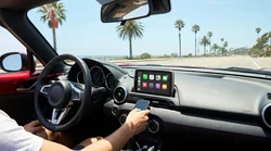 Close-up of a hand tapping an Apple CarPlay screen on the dashboard of a California car rental