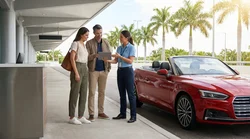 A customer receiving keys for a car rental at a counter with a sunny Florida street in the background