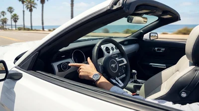 Hand pressing a push-button start on the dashboard of a car rental parked on a sunny California street