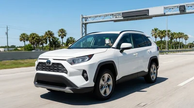 White car rental driving through an electronic toll booth on a Florida highway