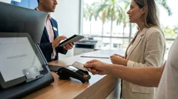 Person handing a credit card to an employee at a car rental counter in Miami