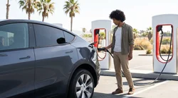 White electric car rental plugged into a Tesla Supercharger station in California