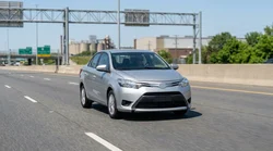 Person driving a car rental on a New York highway with the city skyline in the background