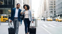Pedestrians with luggage walking outside Penn Station in New York near a car rental storefront