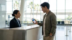 Traveler showing a smartphone screen at a car rental desk in Orlando