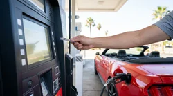 Person typing on a gas station pump keypad while fueling a car rental in California