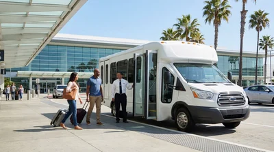 Travelers with luggage boarding a car rental shuttle bus outside the airport in Los Angeles