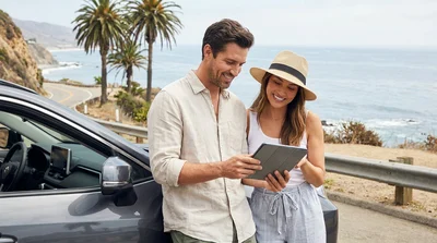 Person driving a car rental along a scenic coastal highway in California