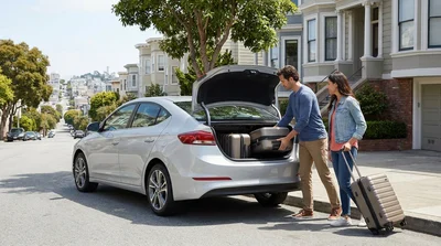 Two suitcases loaded into the open boot of a car rental in San Francisco