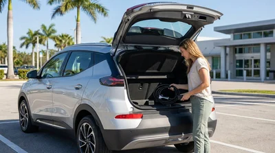 White electric car rental plugged in with a charging cable under palm trees in sunny Florida