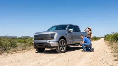 Person inspecting the roof of a white car rental parked on a rugged dirt road in Texas
