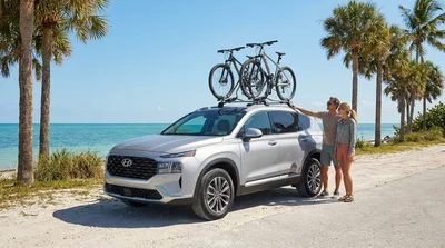 White SUV car rental with a loaded bike rack parked near sunny palm trees in Florida