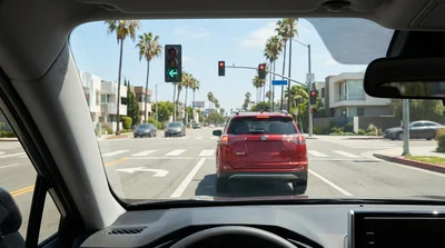 Driver's point of view from a car hire at a busy Los Angeles intersection with traffic lights and palm trees