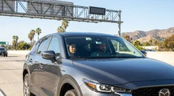 White car rental driving under a Metro ExpressLanes toll sign on a Los Angeles highway
