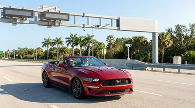 White car rental passing through an electronic toll booth on a sunny Florida highway