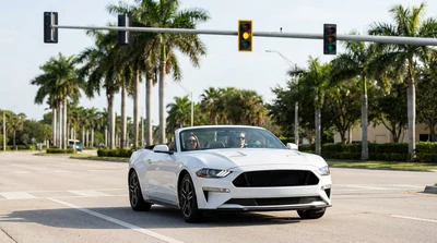Driver in a car rental waiting at a Florida intersection with a flashing red traffic light
