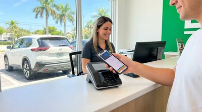 Person using a smartphone at a car hire desk in sunny Miami