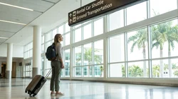 Passengers with luggage walking through the modern Orlando airport terminal toward the car rental desks