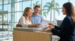 Smiling couple driving a car rental along a sunny coastal road in Florida