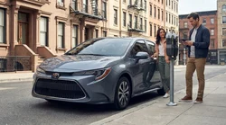 A driver paying at a parking meter next to a car rental on a New York street