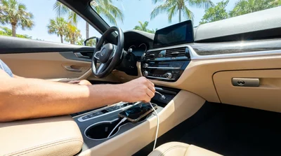 Person plugging a phone charging cable into the dashboard USB port of a Florida car rental