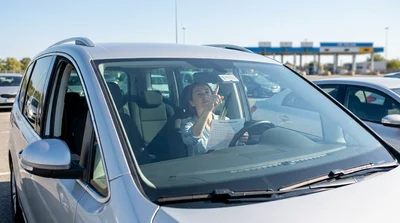 White car rental driving under an electronic toll plaza on a sunny Pennsylvania highway