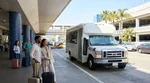 Passengers with luggage boarding a car rental shuttle outside LAX Terminal 5 in Los Angeles