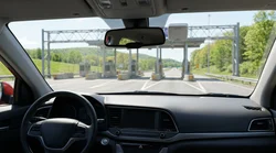 Silver car rental driving on a Pennsylvania highway approaching an electronic toll plaza