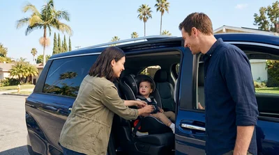 Child safety seat secured in the back of a car rental parked on a sunny Los Angeles street