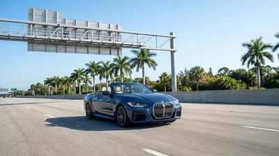 A modern car hire passing under an electronic toll gantry on a sunny Florida highway