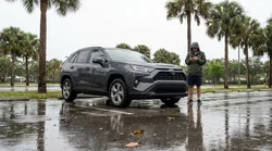 Silver car rental parked in deep flood water on a Florida street under stormy skies