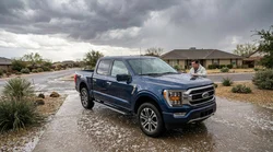 Close up of hail dents on the hood of a white car rental parked on a street in Texas