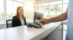Close-up of a customer handing a debit card to an agent at a car rental desk in Florida