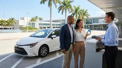Person tapping a smartphone on a payment terminal at a car hire desk in Miami