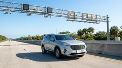 White car rental driving past an electronic toll sign on the I-95 express lanes in Florida