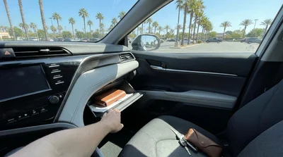 Person checking paperwork inside the glove box of a car rental parked in California