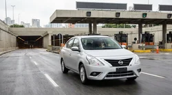 White car rental driving through a New York bridge toll plaza with the city skyline in the background