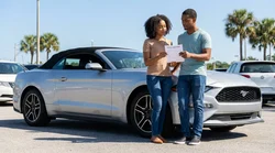 Young woman driving a car rental down a sunny palm-lined coastal road in Florida
