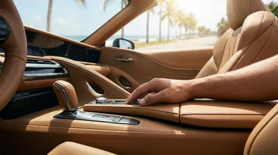 Close up of a hand on a manual gear shifter inside a car rental vehicle parked near a sunny beach in Florida