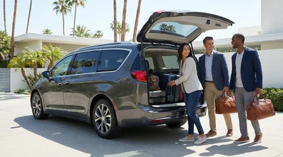 Four adults loading luggage into a spacious car rental parked under palm trees in Los Angeles
