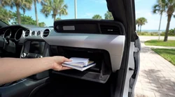 Person checking documents in the open glovebox of a car rental in Florida