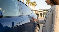 Driver using a smartphone to unlock an electric car rental parked on a sunny California street