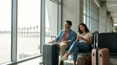 Traveler with luggage waiting by a car hire pickup zone outside a Los Angeles airport