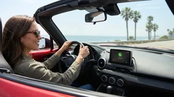 Hands on a steering wheel next to a Bluetooth dashboard screen inside a California car rental