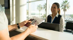 Customer handing travel documents to an agent at a car rental counter in Texas