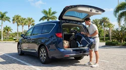 A golfer loading golf clubs into the trunk of an SUV car rental at a sunny Florida golf course