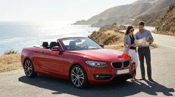 Couple driving a convertible car rental along a scenic coastal highway in California