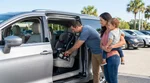 Parent securing a child seat to LATCH points in the back of a car rental in Orlando