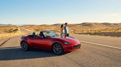 A person driving a car rental along a sunny highway in California