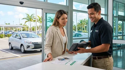 Customer checking a smartphone next to a white car rental parked near palm trees in Miami